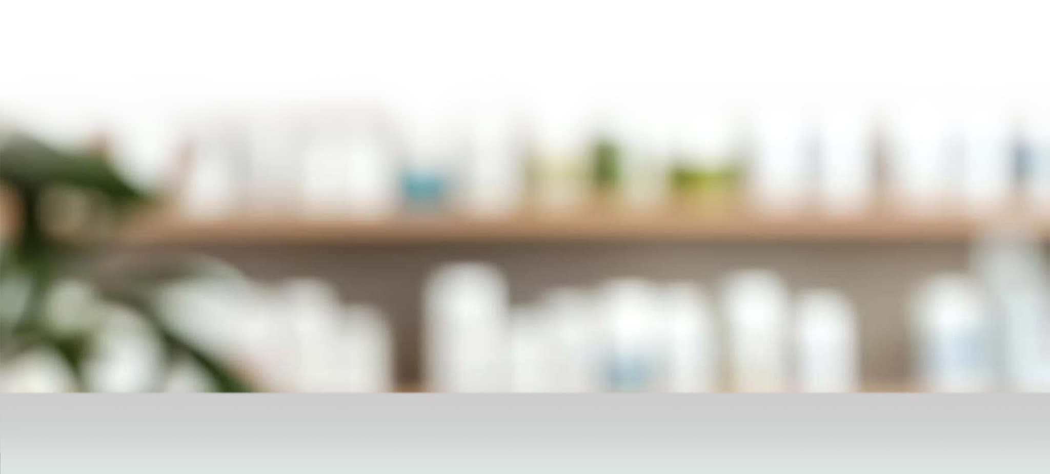 Softly blurred apothecary shelves with greenery.